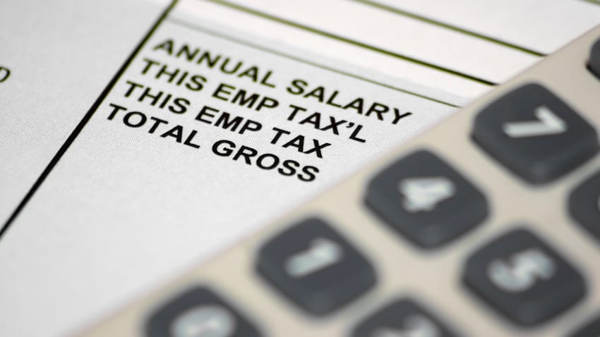 A pay slip underneath an out of focus calculator