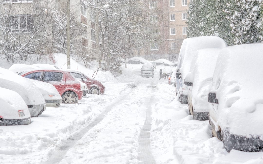 Snowstorm snow-covered street and cars with a lonely pedestrian