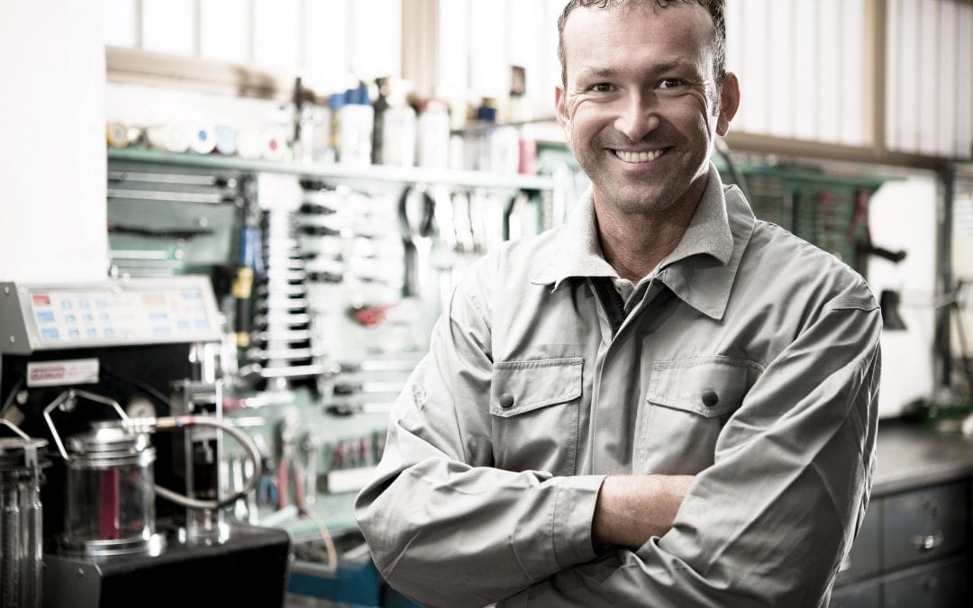 Close-up of a smiling mechanic inside his auto repair shop